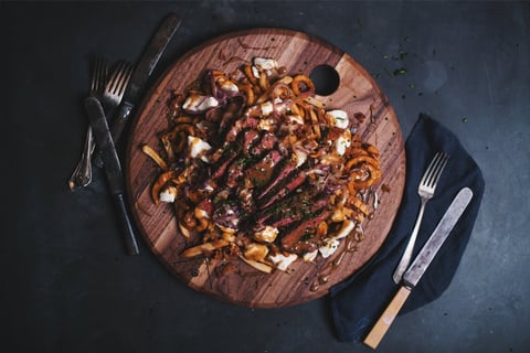 Poutine de luxe avec faux-filet de boeuf, bacon et oignons caramélisés