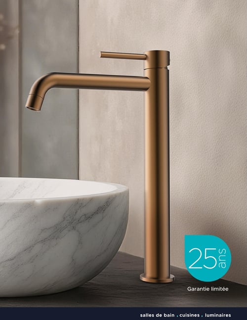 Circulaire Bain Dépôt - Page 7. Une image en gros plan présente un robinet de lavabo moderne de couleur bronze, très élancé, à côté d'un évier vasque rond en marbre blanc veiné. En bas à droite, un macaron turquoise indique "25 ans" avec la mention "Garantie limitée" en dessous. Une bande foncée au bas de la page affiche "salles de bain . cuisines . luminaires".