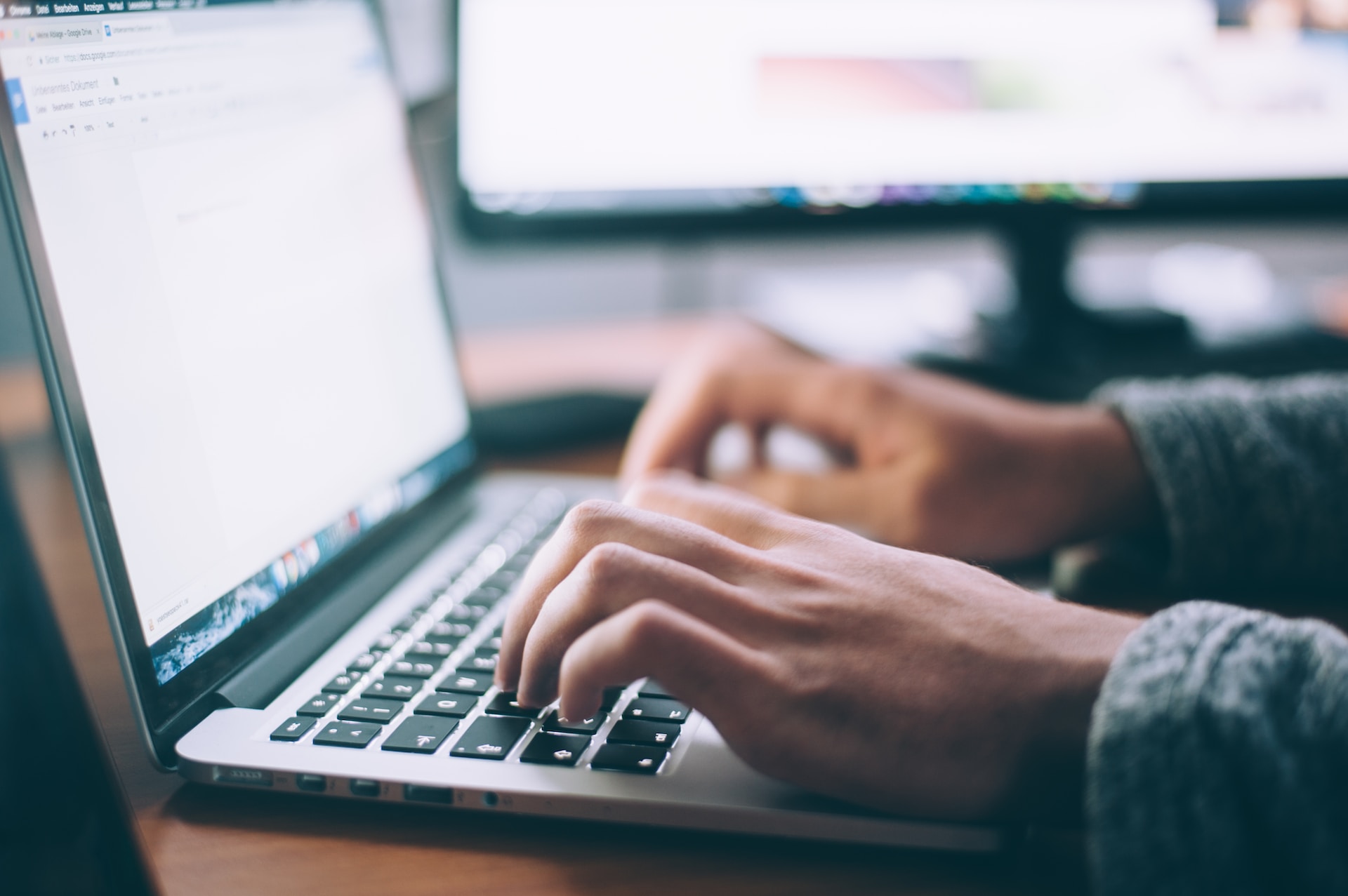 Personne tapant sur un ordinateur portable avec un écran en arrière-plan, illustrant le travail numérique et la productivité