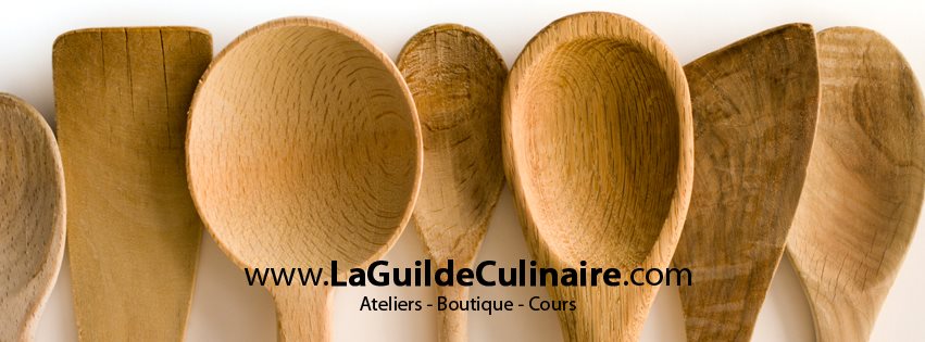 Cuillères en bois artisanales alignées avec le logo de La Guilde Culinaire – Ateliers, Boutique et Cours de cuisine à Montréal